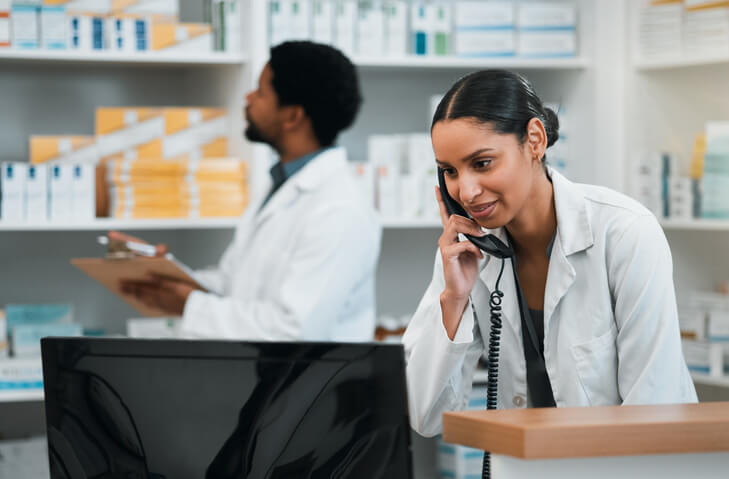woman pharmacist on phone with someone behind her